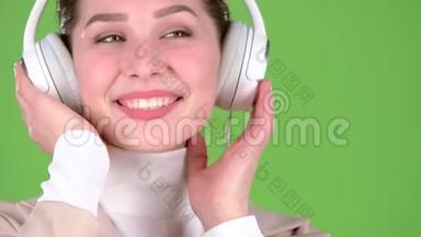 女孩在耳机里听悠扬的歌曲。 绿色屏幕。 关门